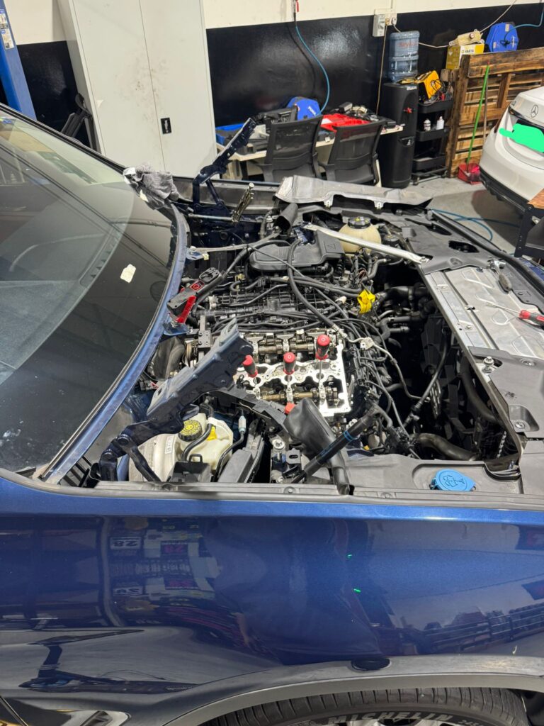 BMW engine bay with valve cover removed during spark plug service at TEC AUTO Services Singapore